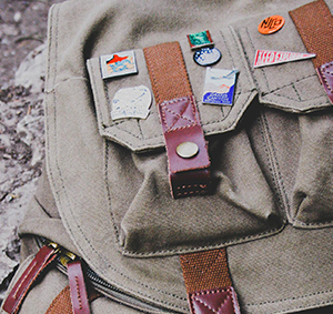 Small camper's pack adorned with numerous enamel pins