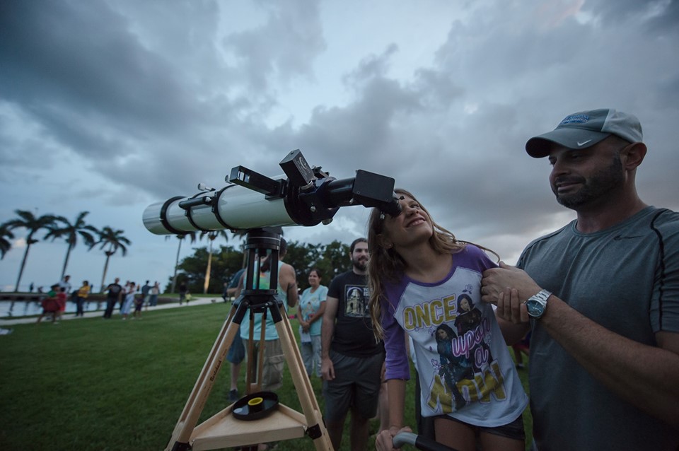 viewers gathered on the main lawn at night in order to examine the full moon with a telescope