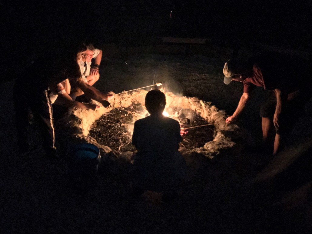 Small group gathered around a campfire during Deering's Night Hike