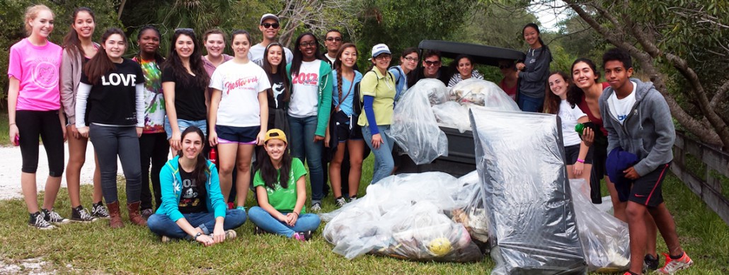 Group of young volunteers gathered together with all of the trash they cleaned up