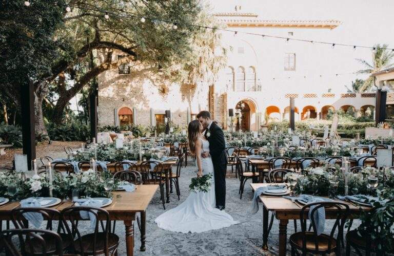 A bride and groom kiss in the middle of the Deering Estate Courtyard as they pose for a photo.