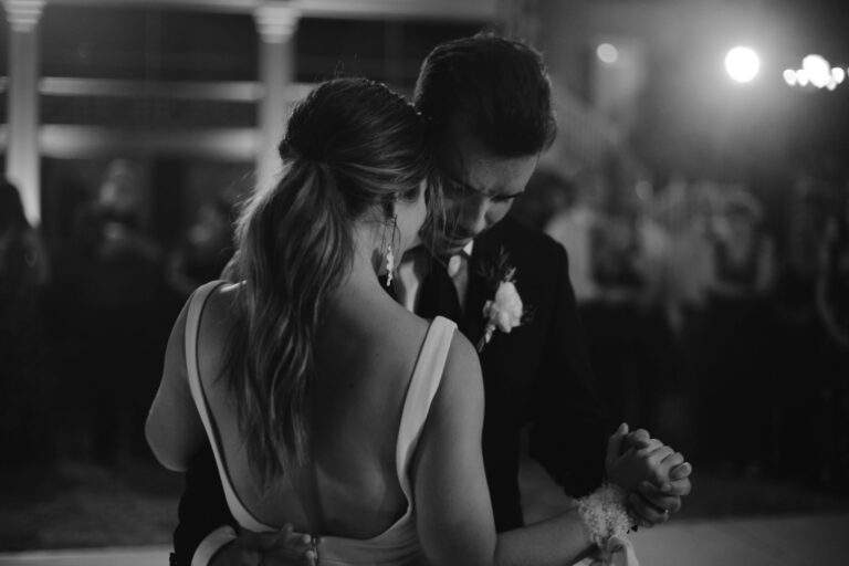 In black and white, a close up of a bride and groom dancing slowly and closely together at their wedding reception.