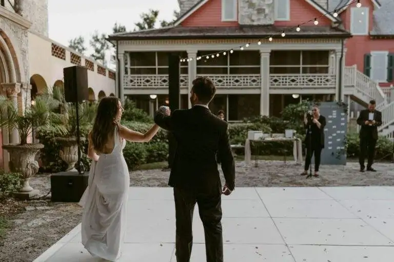 A bride and groom hand-in-hand as they walk out onto the dance floor.