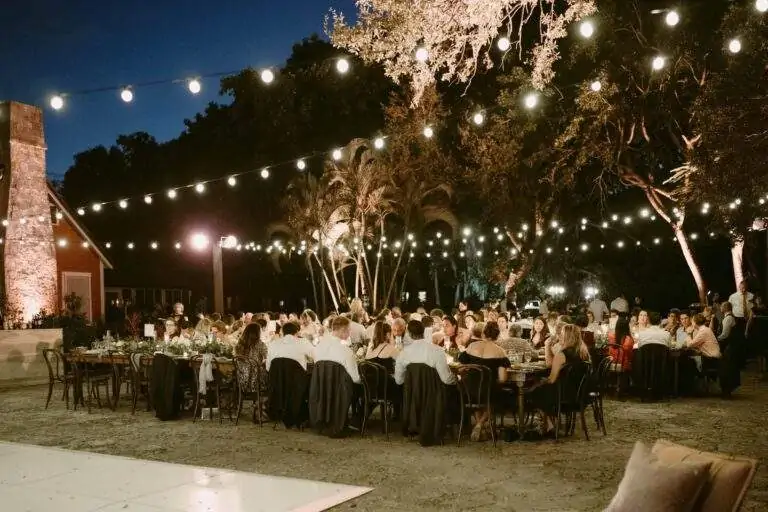 The Deering Estate courtyard decorated with string lights and filled people sitting at tables at a wedding reception.