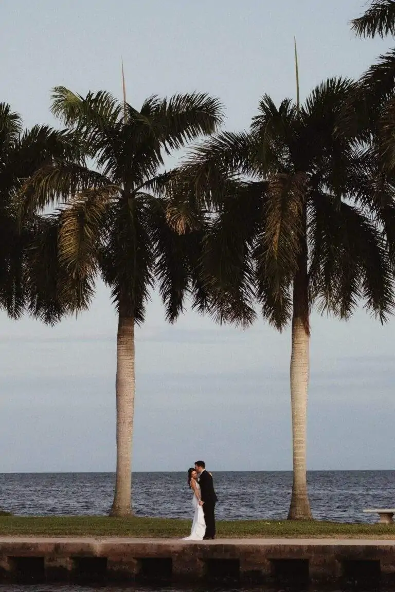 A faraway view of a bride and groom standing on the boat basin jetty at Deering Estate.