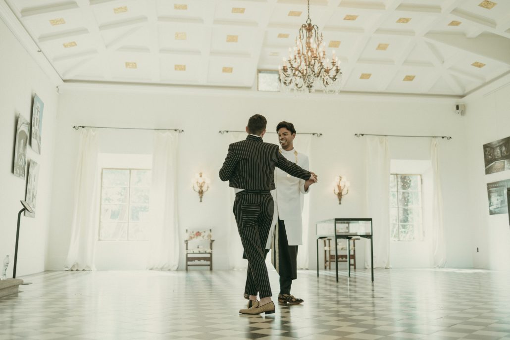 Grooms posing for a picture inside Deering Estate's Stone House grand hall ballroom
