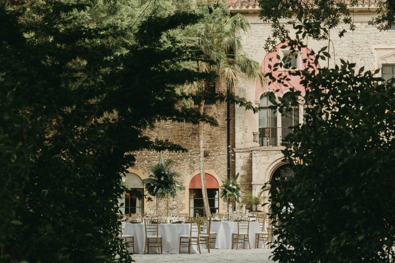 View of the Courtyard wedding reception from the Fig Garden pathway entrance. The Stone House museum is in the background.