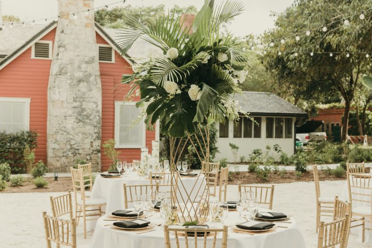 Detail shot of a table with a coastal floral arrangement in Deering Estate's historic Courtyard with the Richmond Cottage Museum in the background