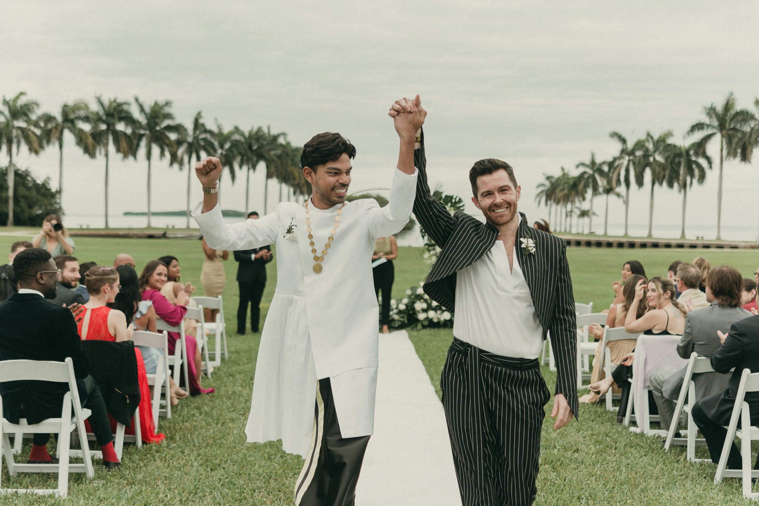 Grooms cheering at the end of their waterfront wedding ceremony