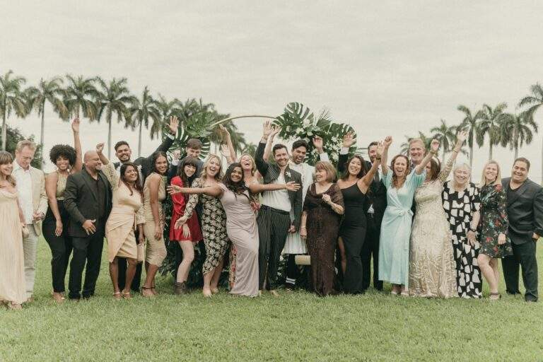 Grooms with their wedding guests taking a photo at Deering Estate's waterfront lawn.