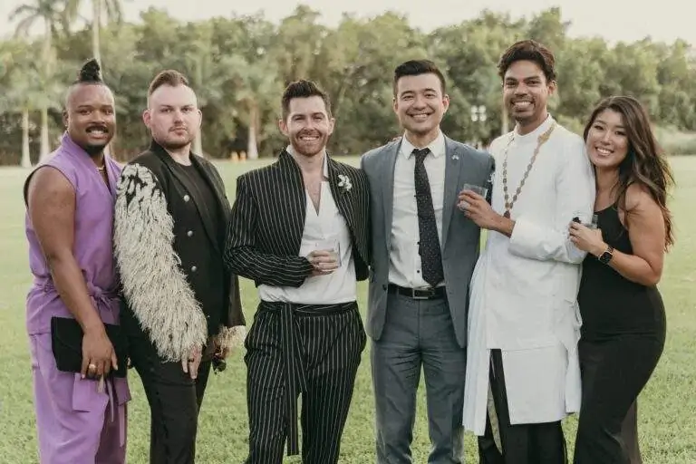 Grooms with some of their wedding guests taking a photo at Deering Estate's waterfront lawn.