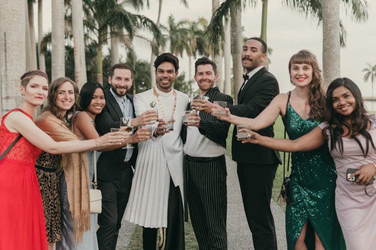 Grooms toasting with some of their wedding guests taking a photo at Deering Estate's Royal Palm Grove