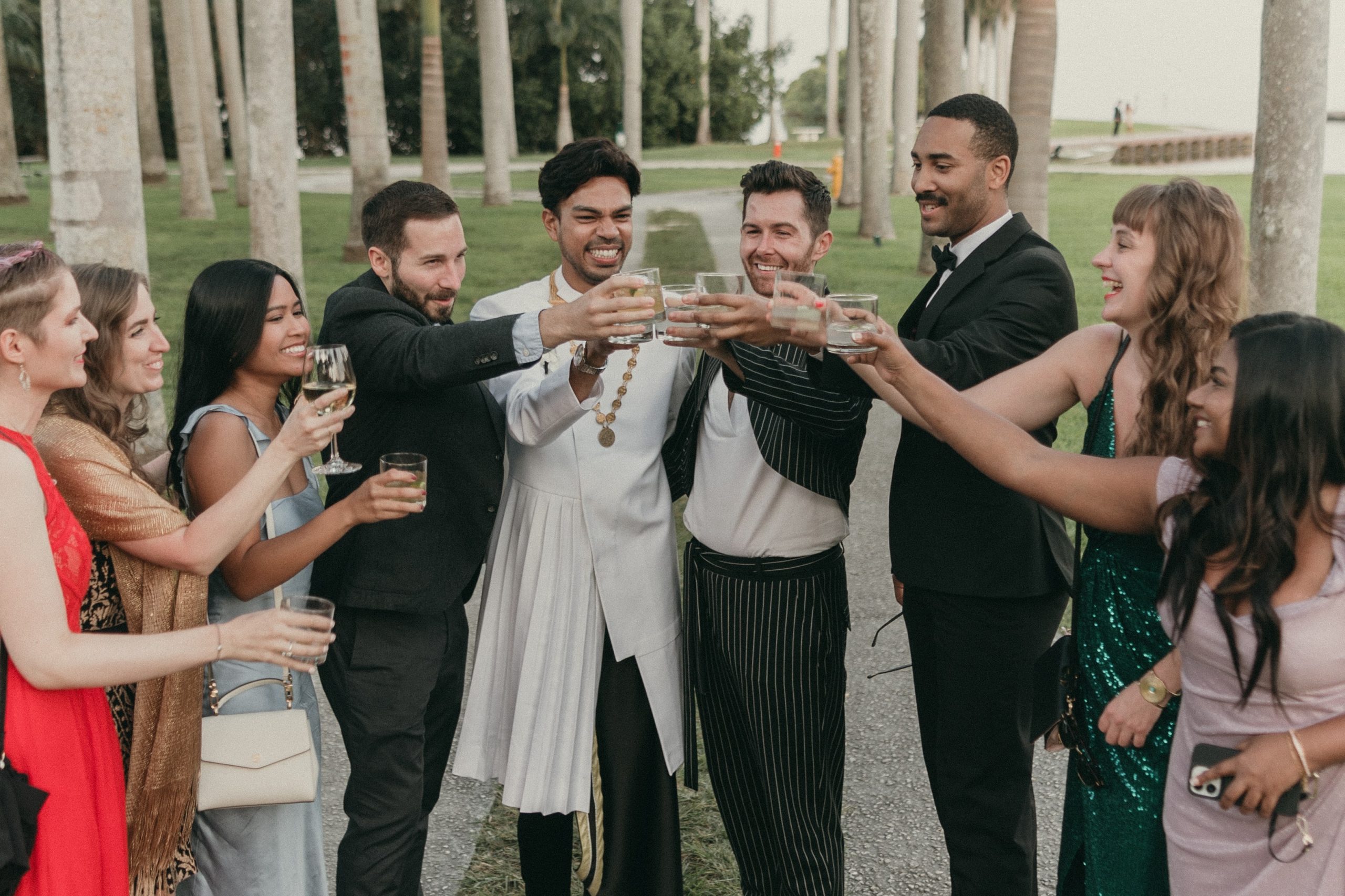Grooms toasting with some of their wedding guests taking a photo at Deering Estate's Royal Palm Grove