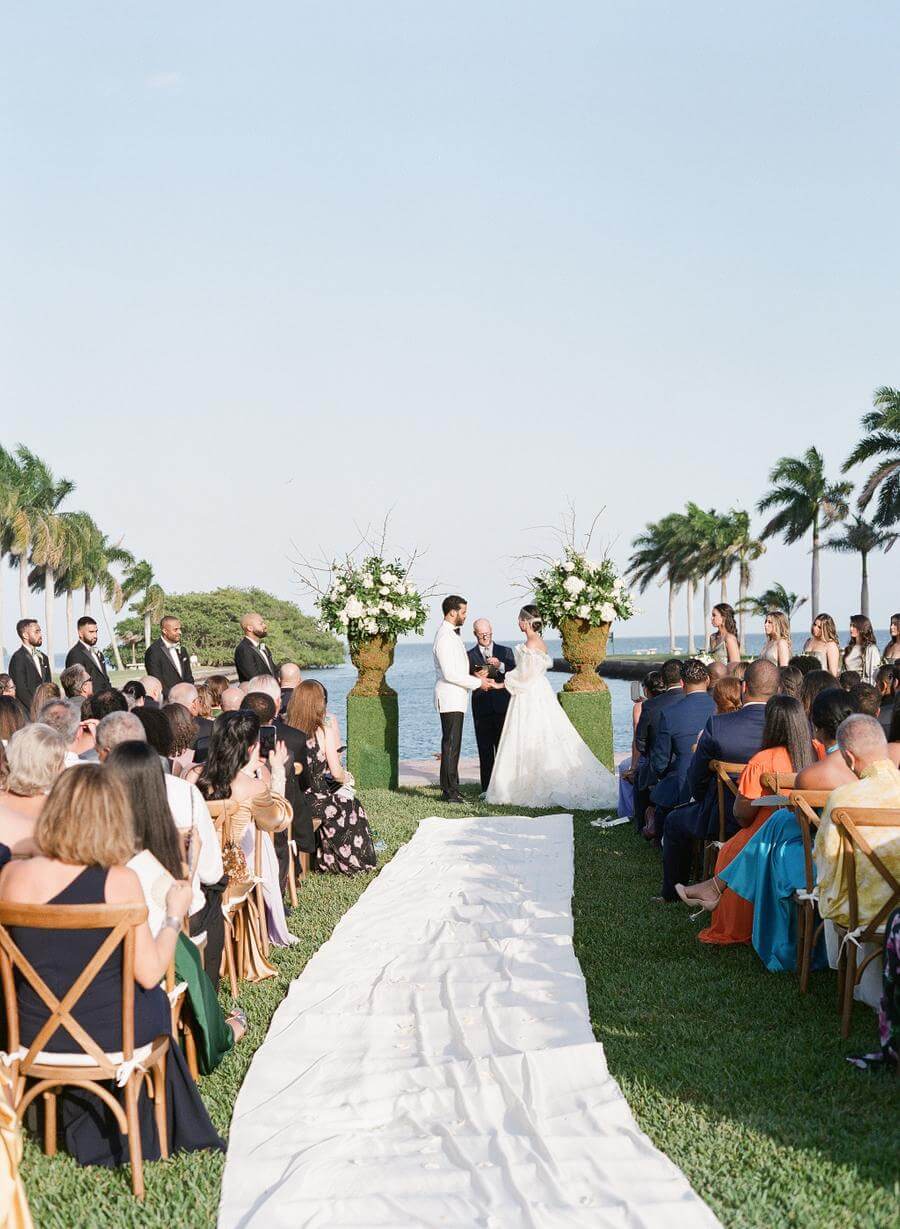 Couple and guests at Deering Estate's Grand Waterfront Lawn during a wedding ceremony