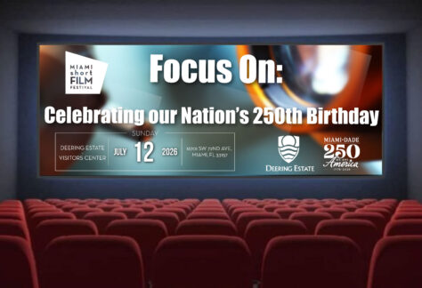 A movie theater screen displays a Miami Short Film Festival graphic announcing an event celebrating the nation’s 250th birthday on July 12, 2026, at the Deering Estate. Logos and event details appear over an abstract cinematic background.