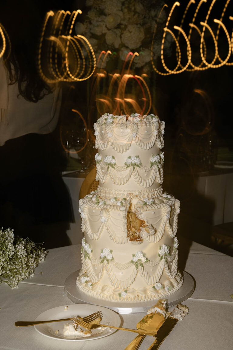 A large two-tiered wedding cake with a slice missing from it.
