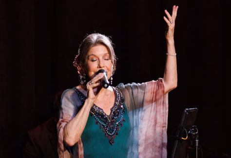 Deering Estate Artist-in-Residence Susana Behar singing with her eyes closed and arm lifted in song.